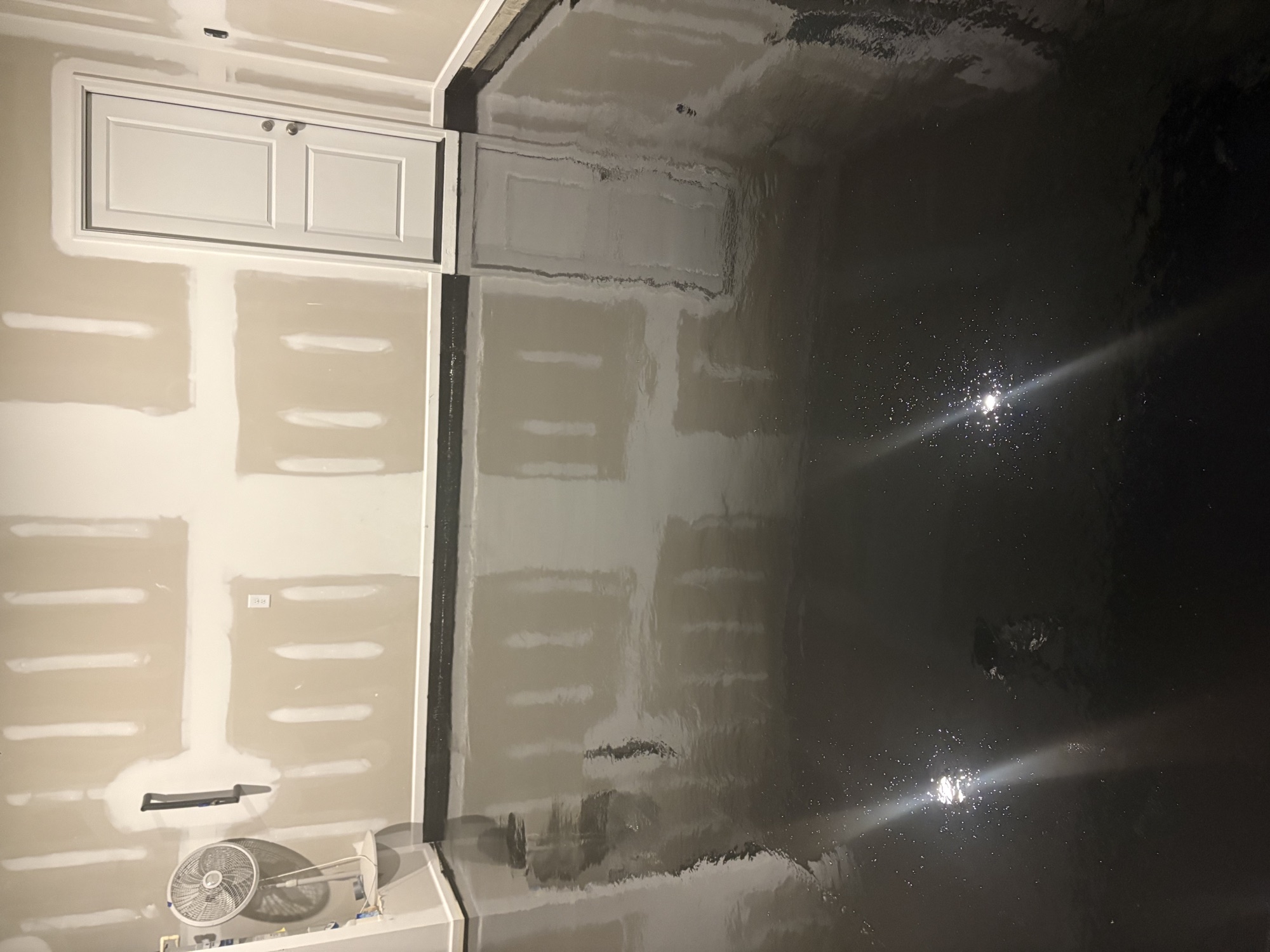 Dark glossy epoxy floor reflecting overhead lights