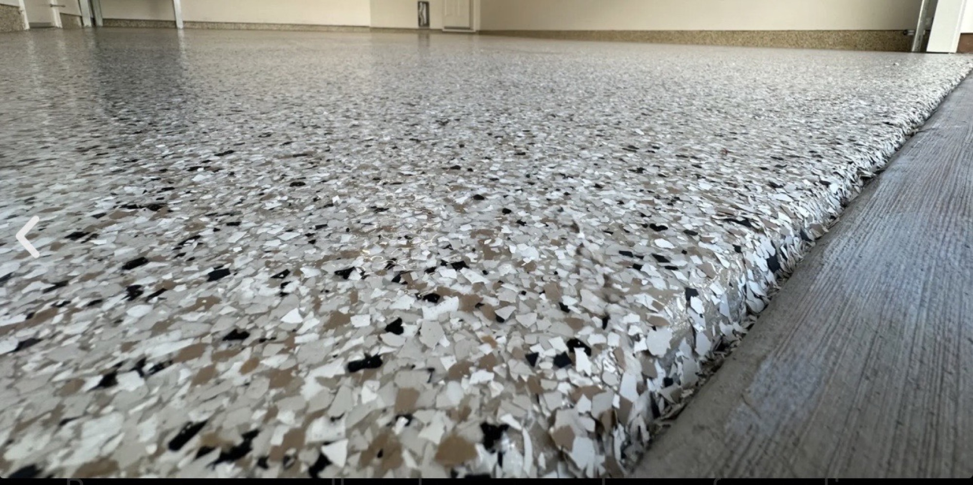 Close-up view of a tan, white, gray, and black decorative flake floor