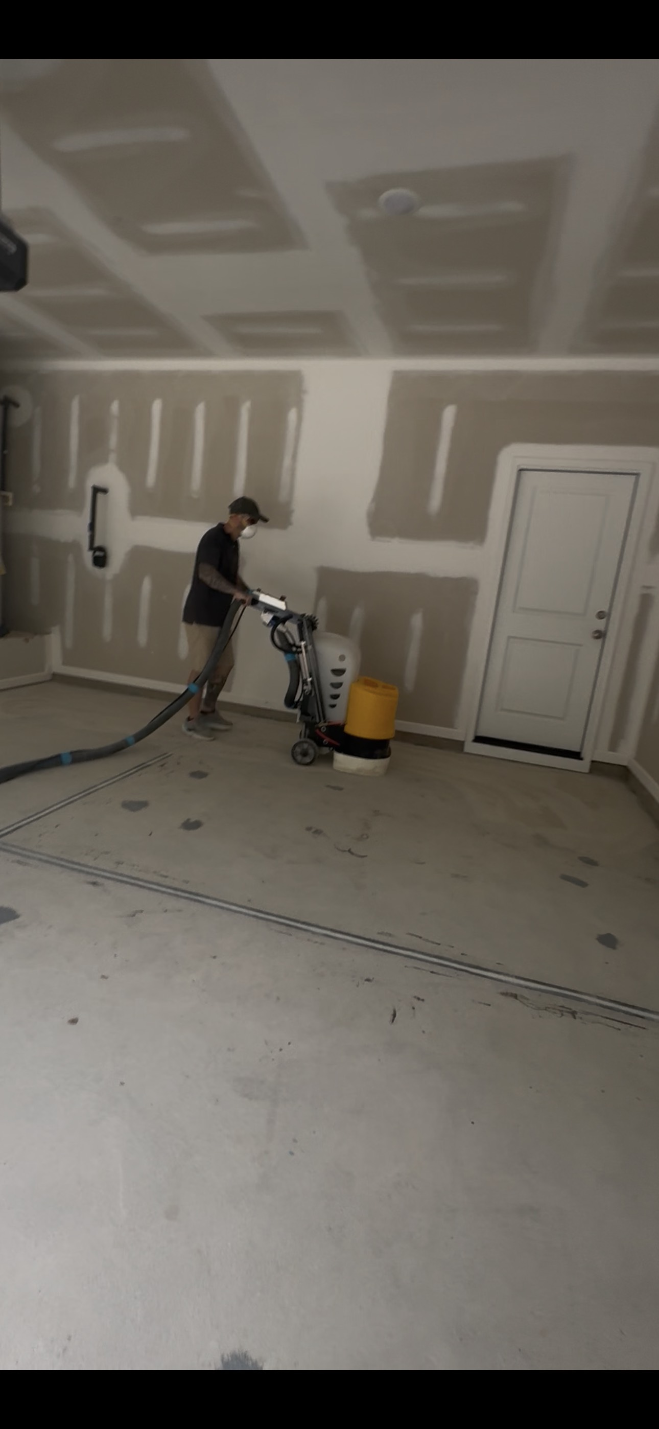 Installer grinding concrete in a residential garage before coating