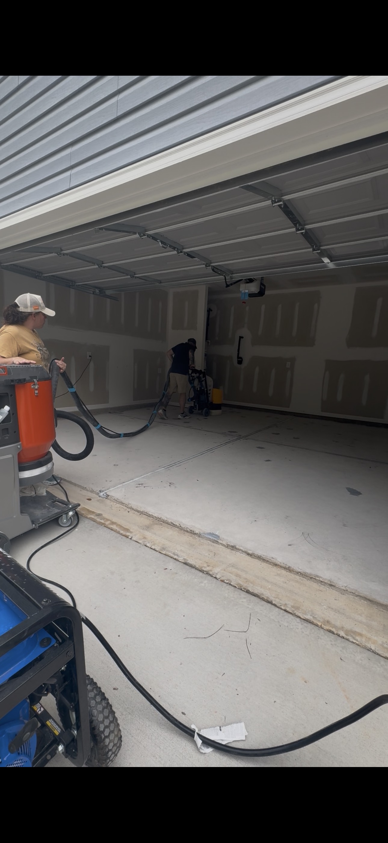 Two-person crew mechanically preparing a residential garage floor
